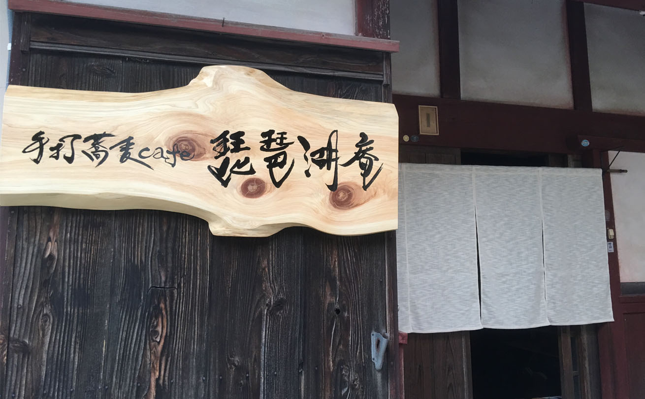 筆文字ロゴを掲げた温かみのある手打蕎麦cafe 琵琶湖庵の木製看板