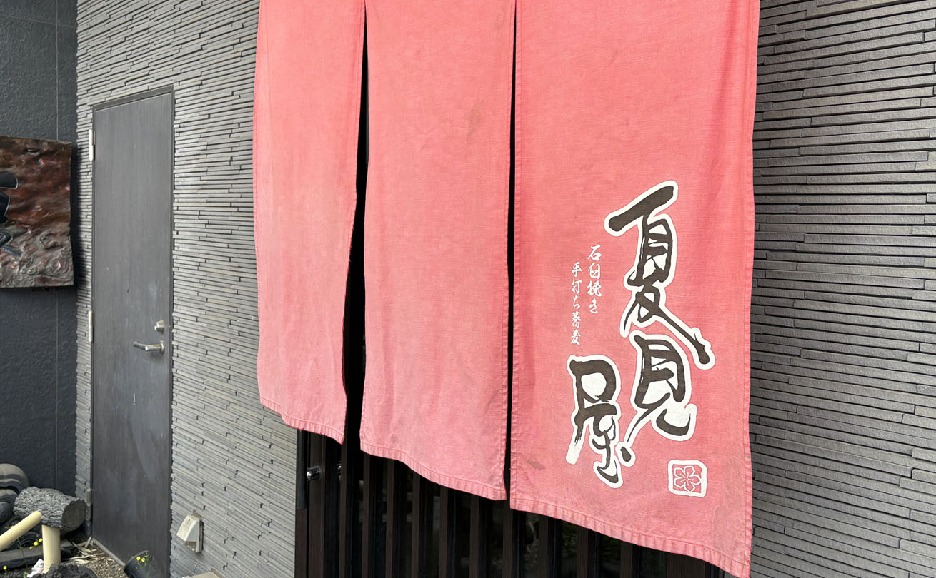 赤い暖簾に白く染め抜かれた夏見屋の筆文字ロゴ