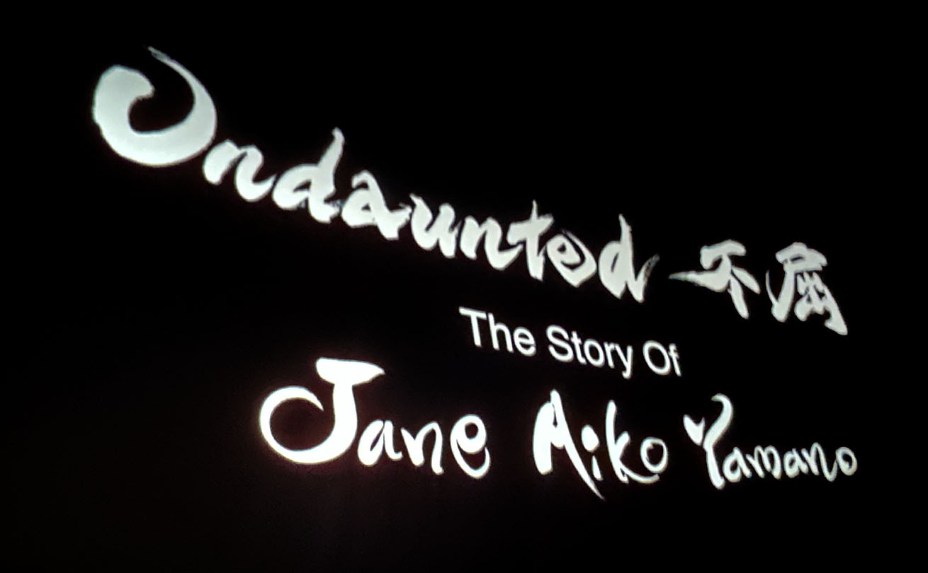スクリーンに映し出された「Undaunted 不屈」と「Jane Aiko Yamano」の筆文字