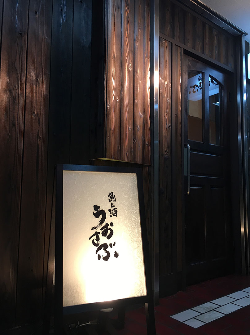 店の玄関に置かれた魚と酒 うおさぶの行灯型看板